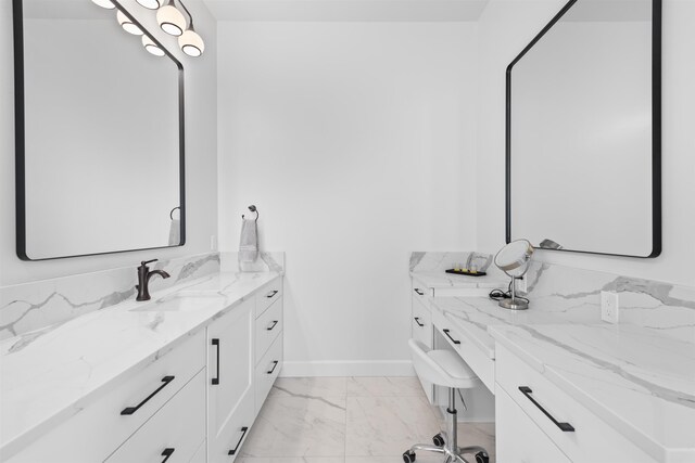 full bathroom featuring marble finish floor, two vanities, and a sink