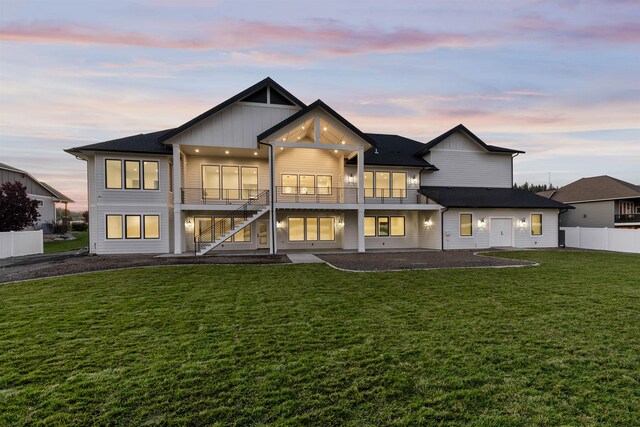 back of house at dusk featuring a yard, a patio, board and batten siding, and fence