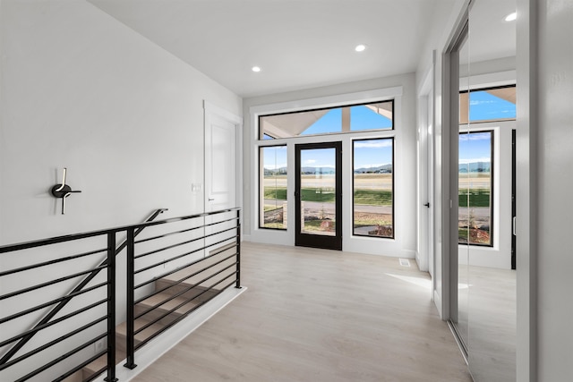 corridor featuring an upstairs landing, recessed lighting, and light wood-style flooring