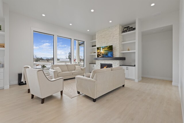 unfurnished living room featuring recessed lighting, a fireplace, baseboards, and light wood-style floors