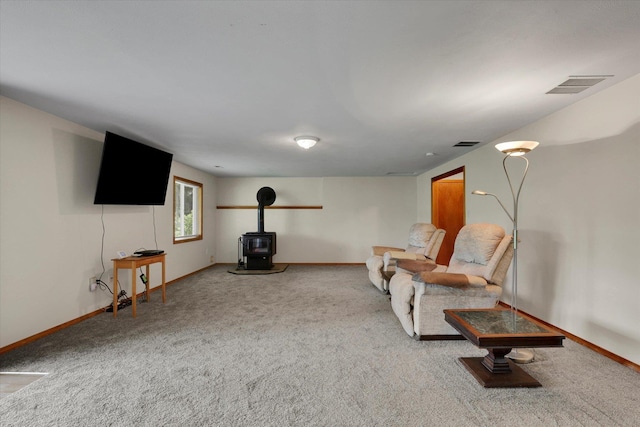 sitting room featuring visible vents, carpet flooring, and a wood stove