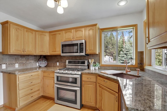 kitchen featuring a sink, light stone countertops, appliances with stainless steel finishes, and light brown cabinets