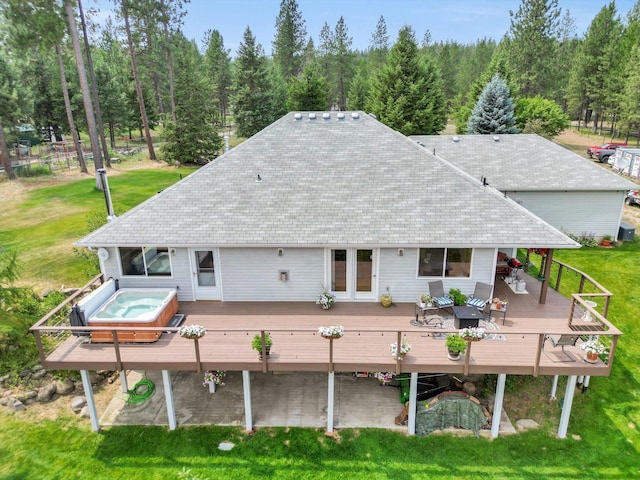 back of house with a tile roof, an outdoor hot tub, a lawn, and a wooden deck