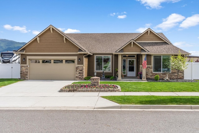 craftsman-style house with stone siding, concrete driveway, and fence