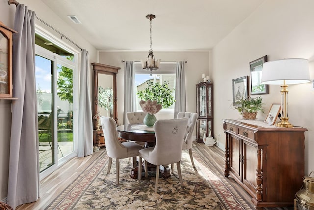 dining space featuring light wood finished floors, plenty of natural light, and visible vents