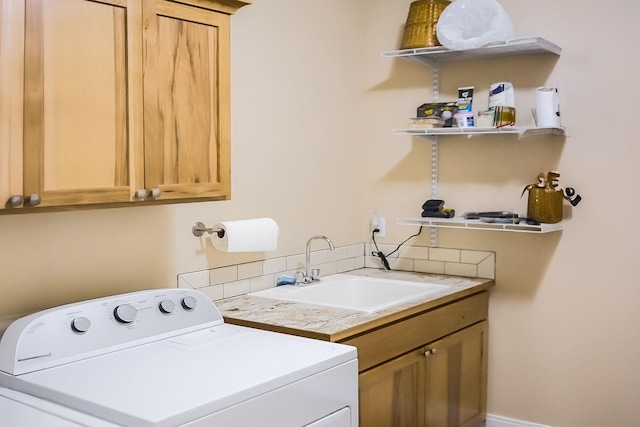 laundry room with a sink, baseboards, cabinet space, and washer / dryer