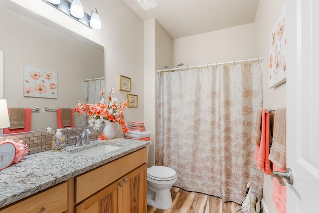 full bath with toilet, curtained shower, tasteful backsplash, wood finished floors, and vanity