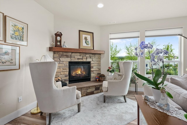 living room featuring wood finished floors, visible vents, baseboards, a fireplace, and recessed lighting