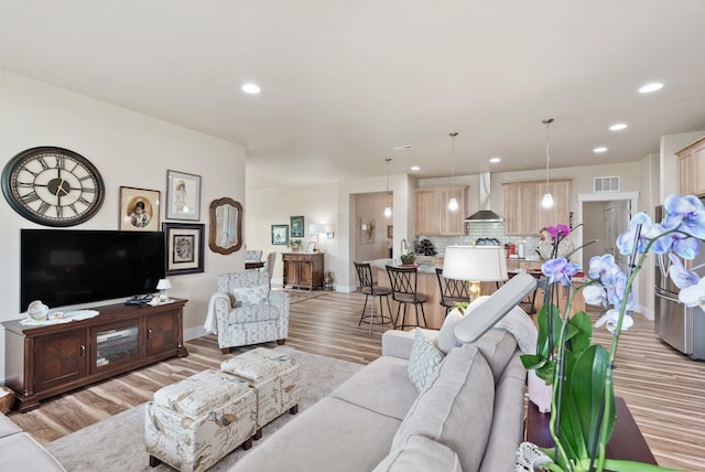 living area with recessed lighting, visible vents, baseboards, and light wood finished floors