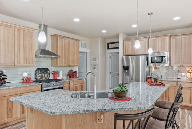 kitchen with visible vents, light brown cabinetry, a sink, appliances with stainless steel finishes, and wall chimney exhaust hood