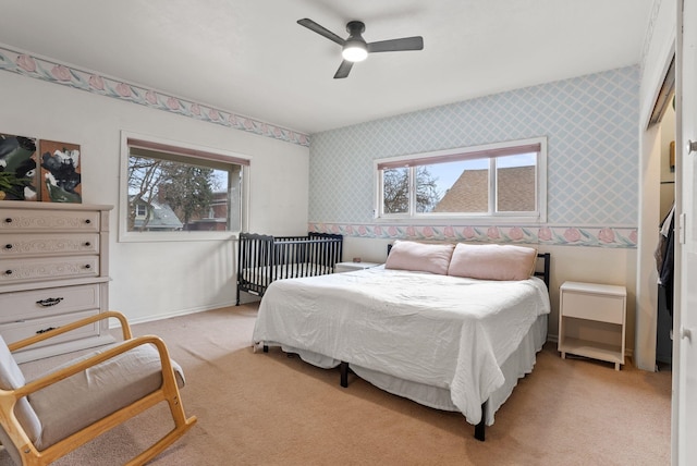 bedroom featuring baseboards, light colored carpet, a ceiling fan, and wallpapered walls