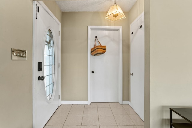 entryway with light tile patterned floors, a textured ceiling, and baseboards