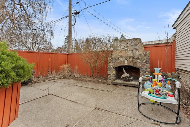 view of patio / terrace with an outdoor stone fireplace and a fenced backyard