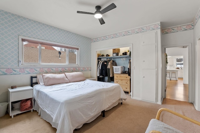 bedroom featuring a closet, light colored carpet, wallpapered walls, and ceiling fan