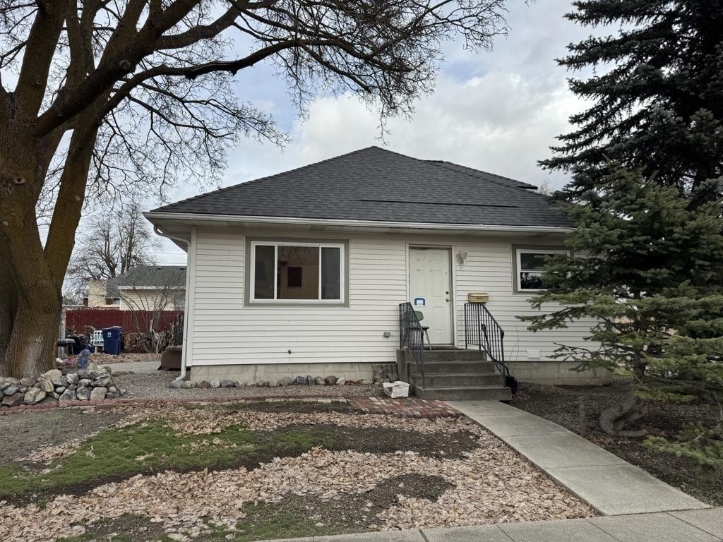 bungalow-style home featuring fence and roof with shingles