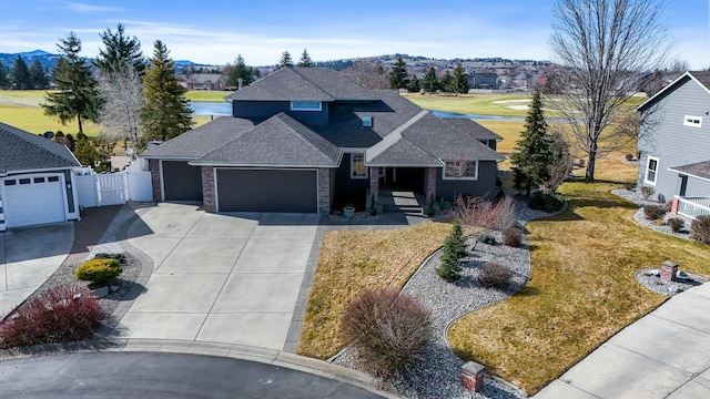 traditional home featuring fence, concrete driveway, roof with shingles, an attached garage, and a gate