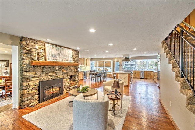 living room with stairs, recessed lighting, a fireplace, and wood-type flooring