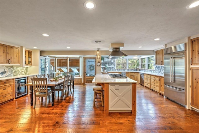 kitchen featuring dark wood-style floors, a kitchen breakfast bar, appliances with stainless steel finishes, and beverage cooler