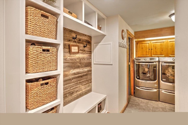 laundry area with cabinet space, separate washer and dryer, and wood walls