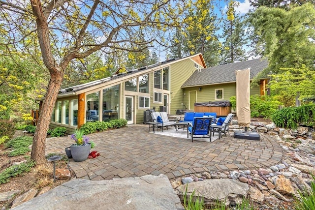 rear view of house featuring a patio area, a hot tub, outdoor lounge area, and a sunroom