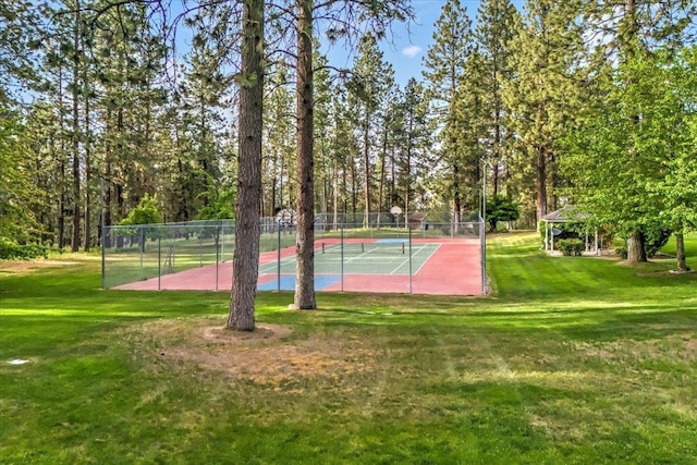 view of tennis court featuring a lawn and fence