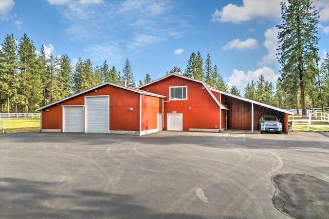 view of front of home with a detached garage, an outdoor structure, and fence