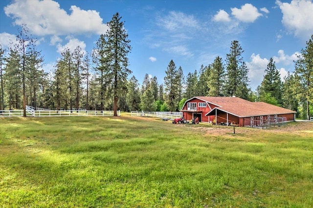 view of yard featuring a rural view, an outbuilding, and fence