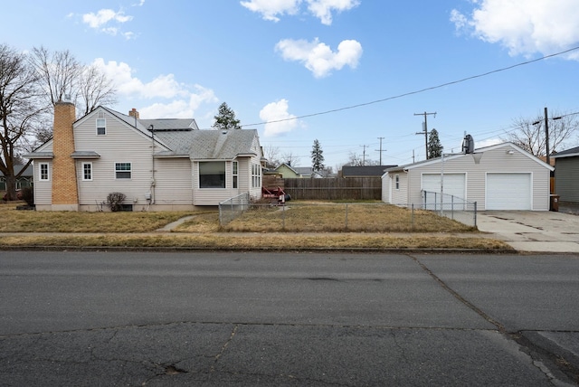 view of front of home featuring an outbuilding, roof mounted solar panels, a garage, fence private yard, and a chimney