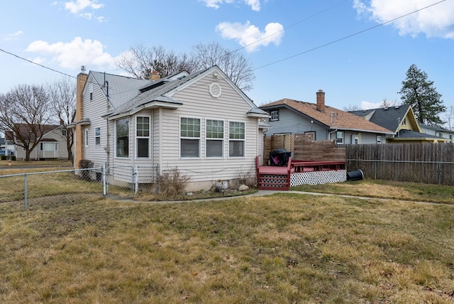 rear view of property featuring a lawn, a deck, a gate, a fenced backyard, and a chimney