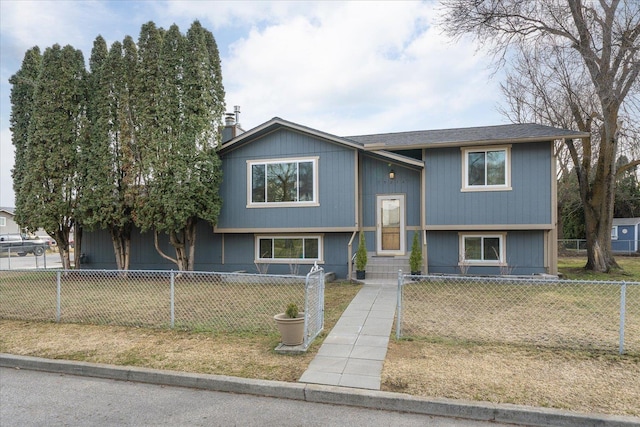 raised ranch featuring a fenced front yard, entry steps, and a front yard