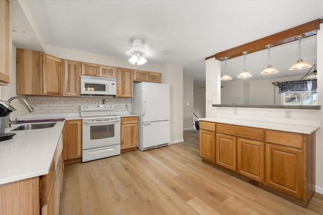 kitchen featuring a sink, white appliances, light wood-style floors, light countertops, and decorative backsplash