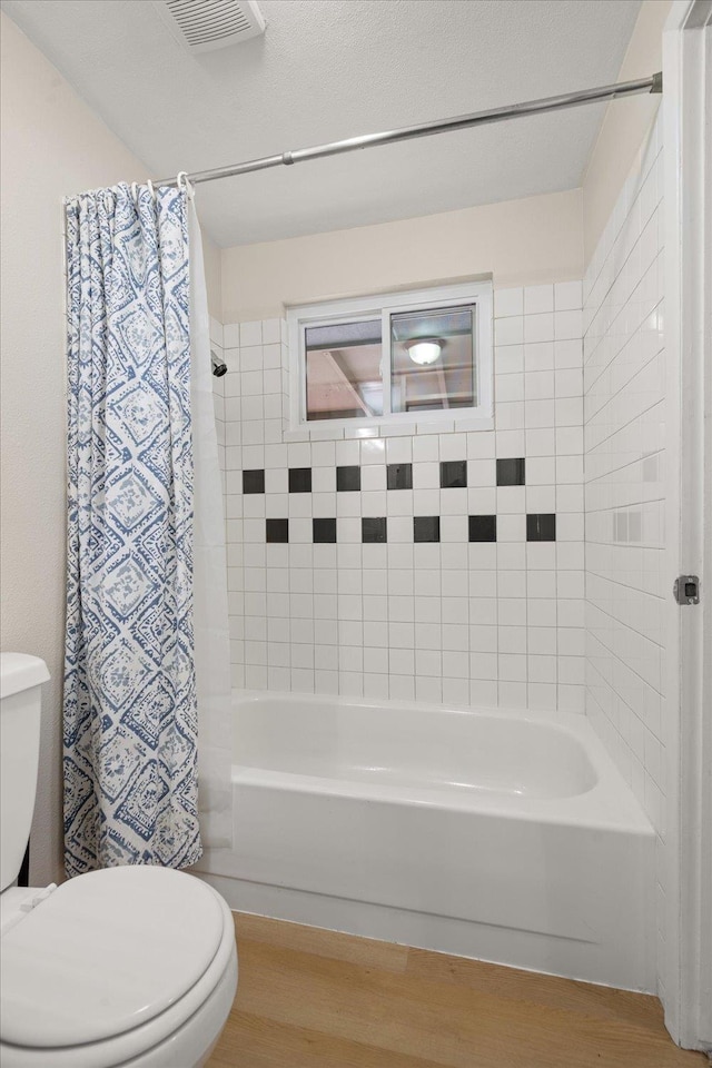 full bath with visible vents, toilet, wood finished floors, and shower / bath combination with curtain