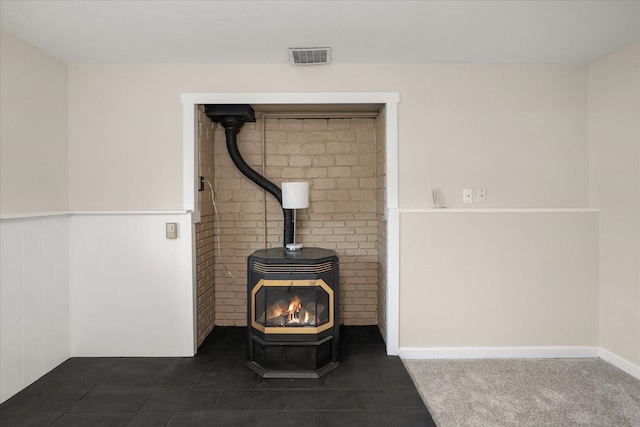 interior details featuring visible vents, a wood stove, carpet, and a wainscoted wall