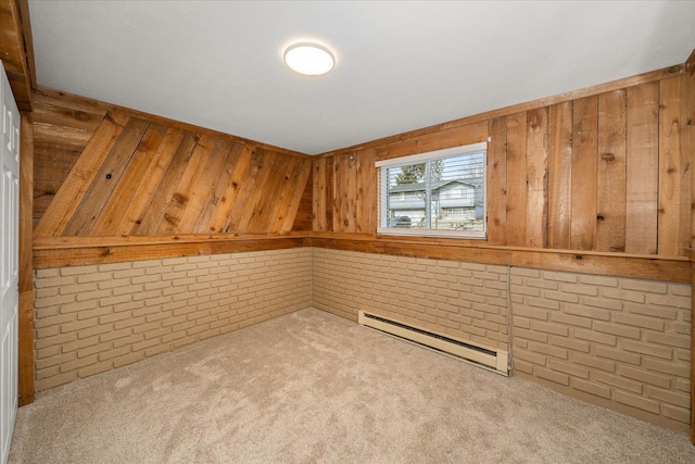 carpeted spare room featuring a baseboard heating unit, brick wall, and wood walls