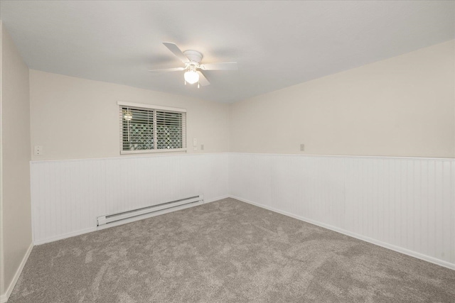 carpeted empty room with a wainscoted wall, ceiling fan, and a baseboard radiator