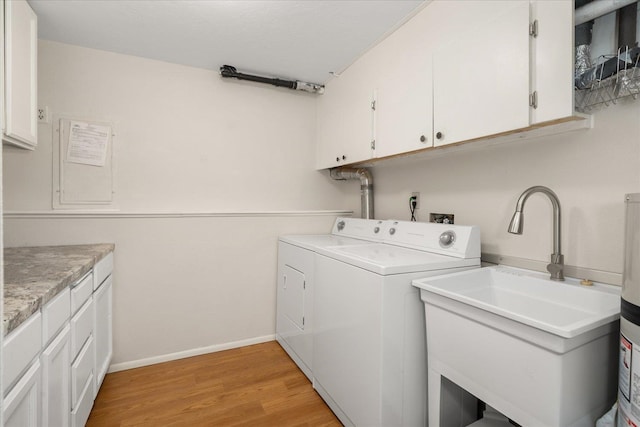 clothes washing area with a sink, cabinet space, separate washer and dryer, light wood finished floors, and baseboards