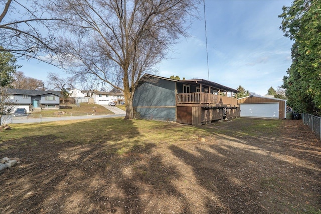 rear view of property featuring an outbuilding, a yard, and fence