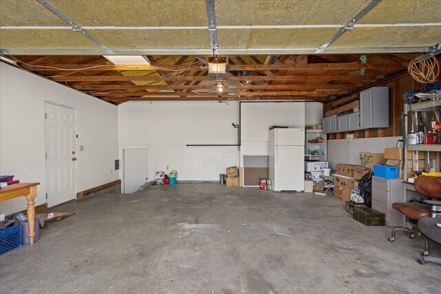 garage with a garage door opener and freestanding refrigerator