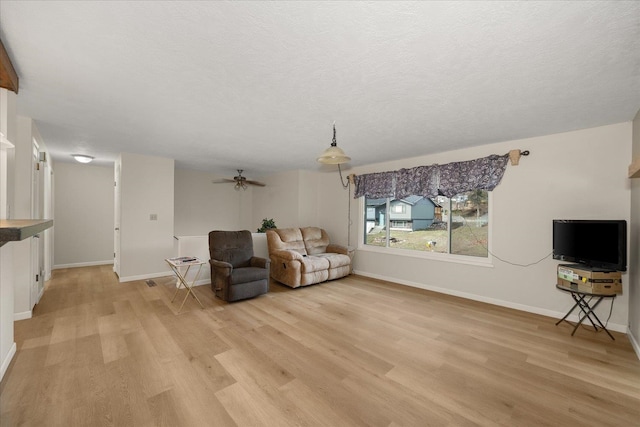 unfurnished room with a ceiling fan, baseboards, light wood finished floors, and a textured ceiling