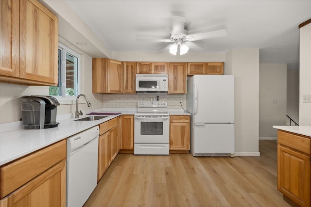 kitchen with light wood finished floors, a sink, tasteful backsplash, white appliances, and light countertops