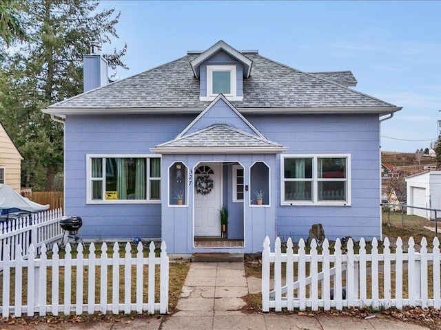 bungalow-style home with a fenced front yard, a chimney, and a shingled roof