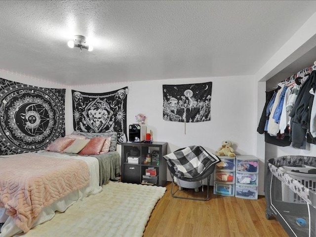 bedroom with a textured ceiling and wood finished floors