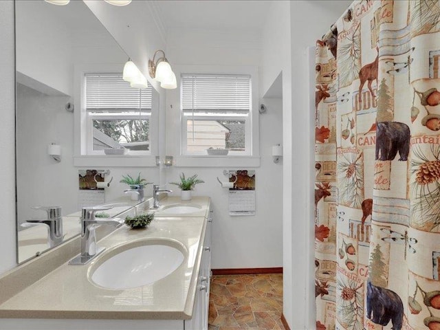 bathroom with a sink, stone finish flooring, baseboards, and double vanity