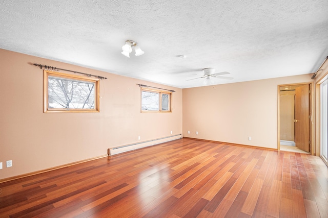 empty room with light wood-type flooring, baseboards, baseboard heating, and a textured ceiling