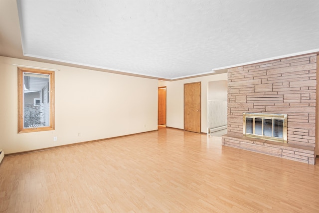 unfurnished living room featuring wood finished floors, baseboards, a stone fireplace, a textured ceiling, and crown molding