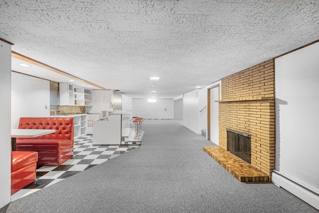 finished below grade area with tile patterned floors, a brick fireplace, a textured ceiling, and a baseboard radiator