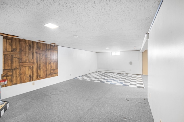 basement featuring wood walls, a textured ceiling, a baseboard heating unit, tile patterned floors, and carpet flooring