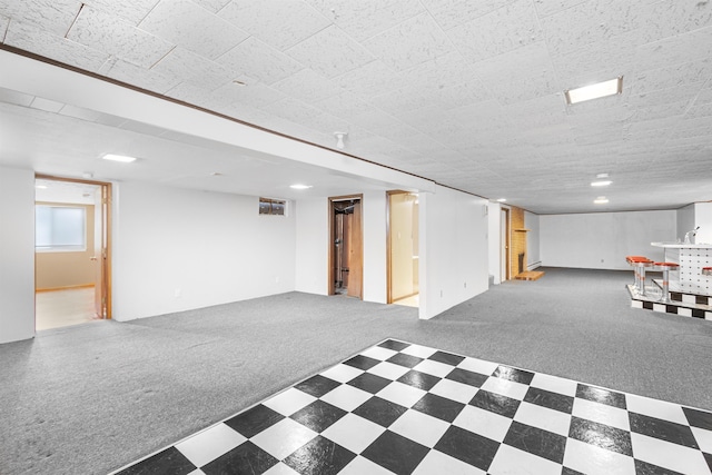 below grade area featuring tile patterned floors and carpet flooring