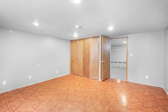 unfurnished bedroom featuring light floors, a closet, and a textured ceiling