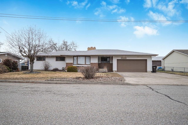 ranch-style home with driveway, fence, an attached garage, brick siding, and a chimney